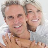 Affectionate couple smiling at camera at home in bedroom